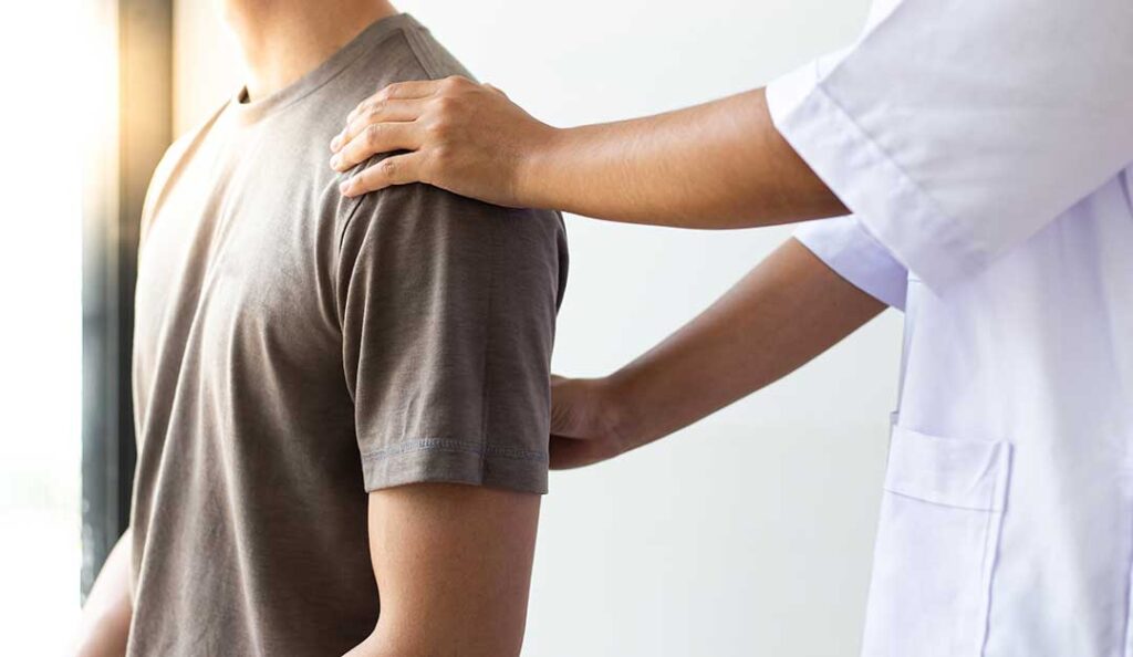 A person in comfortable clothing receiving a gentle spinal adjustment from a professional in a clinical setting.