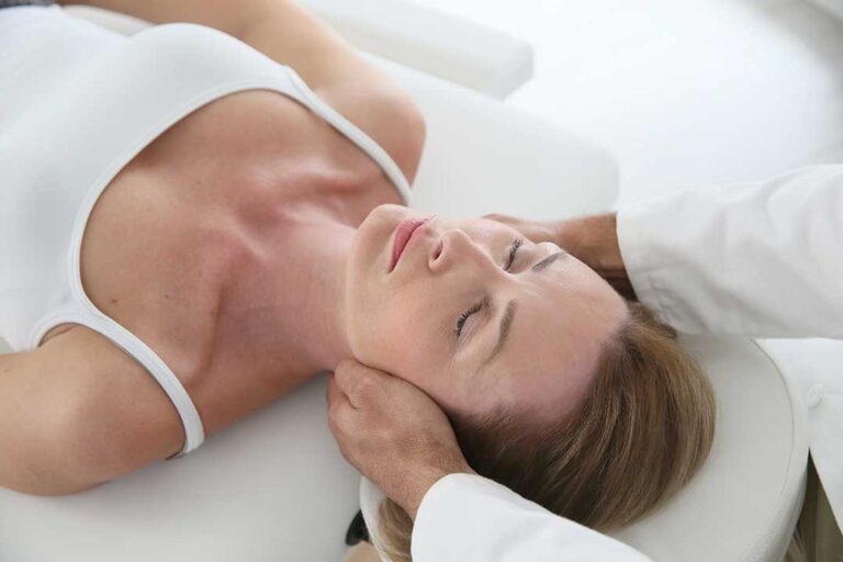 Person sitting and gently massaging their upper shoulder to relieve muscle discomfort.